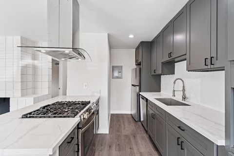 an all white kitchen with marble counter tops and stainless steel appliances